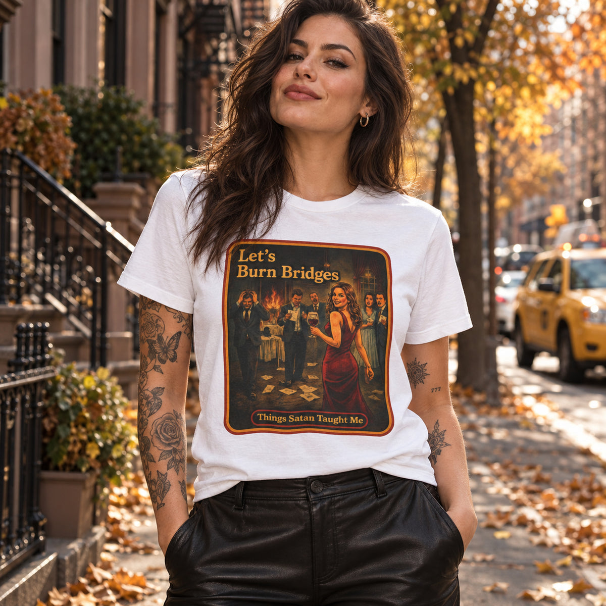 Woman in a white Let's Burn Bridges tee and leather trousers on an autumn city street