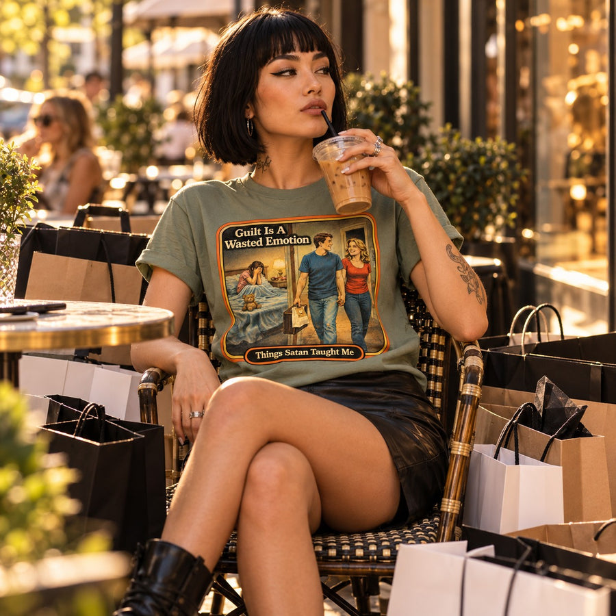 Model sitting in the Guilt Is A Wasted Emotion tee in sage by Things Satan Taught Me