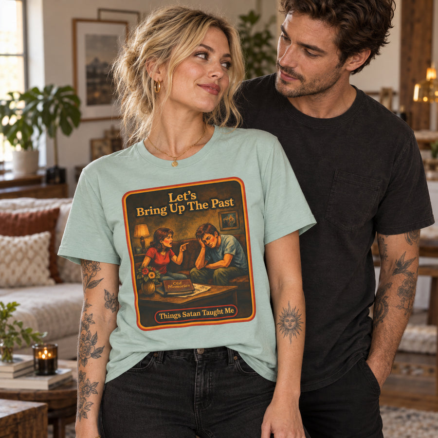 Woman in a pale green Let's Bring Up The Past tee standing beside a man in a black tee in a living room